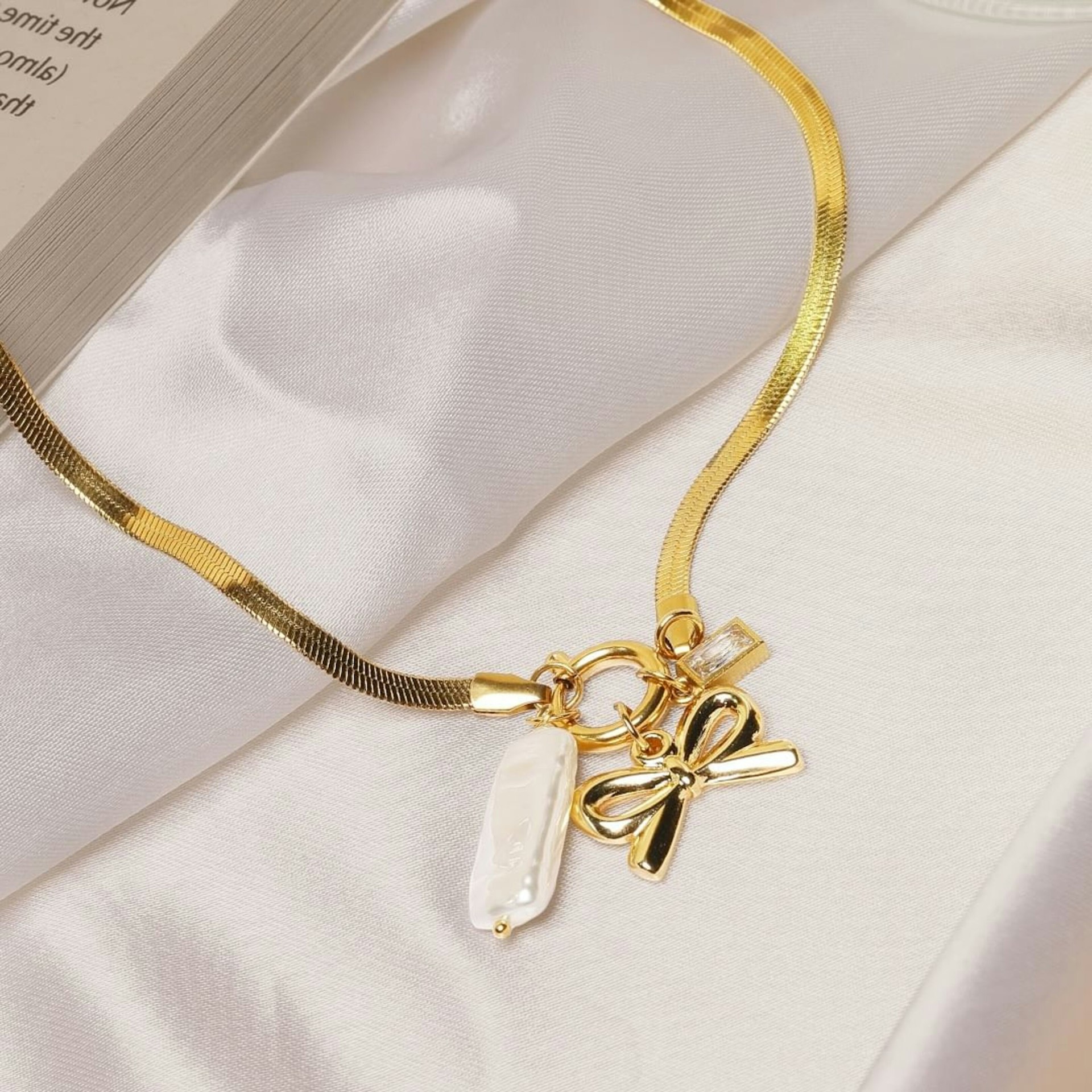 A book and a necklace on a bed